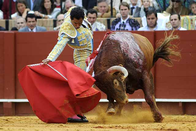 Alargándole la embestida al toro y estirando el brazo.