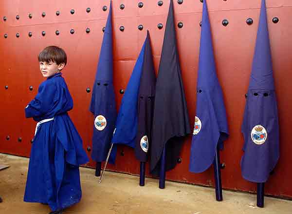 Un joven nazareno junto a una puerta de la Maestranza.