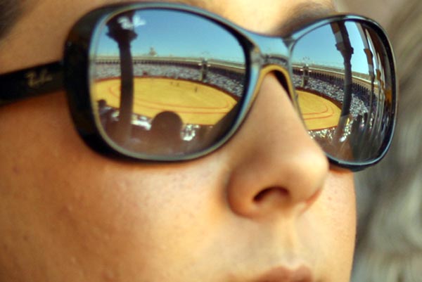 La plaza de la Maestranza reflejada en su integridad en las gafas de sol de una aficionada. (FOTO: Javier Martínez)