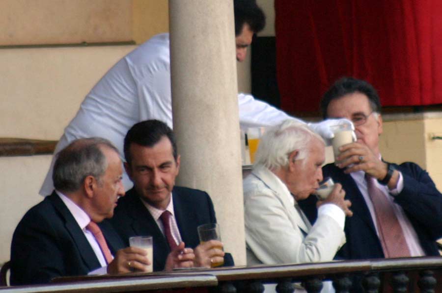 Miembros de la Real Maestranza consumiendo bebidas en vaso de cristal durante el festejo.