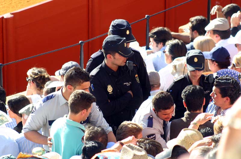 Tres policías y dos vigilantes de la empresa intentan parar a los espectadores que sólo quieren llegar al asiento que han pagado a alto precio.