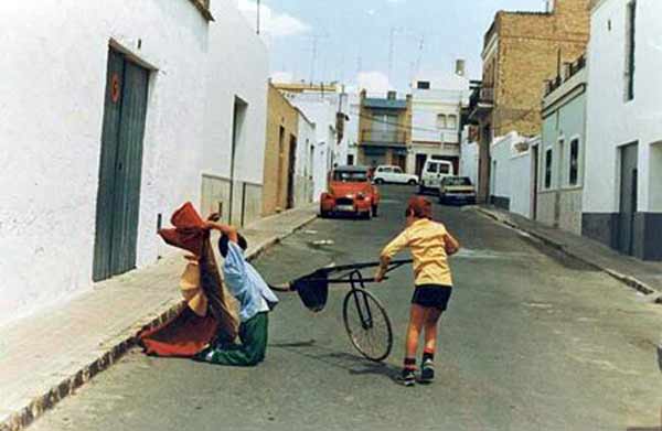 Morante niño jugando al toro en la puerta de su casa en La Puebla del Río mientras su primo y actual mozo de espadas, Juan Carlos Morante, le embiste con un pequeño carretón.