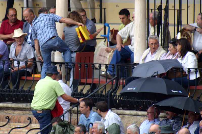 Varios aficionados se ponen a salvo de la lluvia subiendo a las gradas.