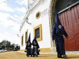 Nazarenos del Baratillo pasan por la Maestranza hacia la capilla de la Hermandad.