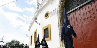 Nazarenos del Baratillo pasan por la Maestranza hacia la capilla de la Hermandad.