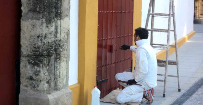 Un operario repasa de pintura una puerta de acceso a la plaza de Sevilla. (FOTO: Javier Martínez)