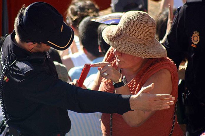 Una señora mayor señala a su asiento para poder acceder, y el policía le corta el paso indicándole que baje a los pasillos interiores.