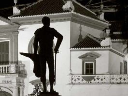 La silueta del monumento de Pepe Luis, con la muleta hecha un cartucho de pescado, se perfila frente a la Maestranza.