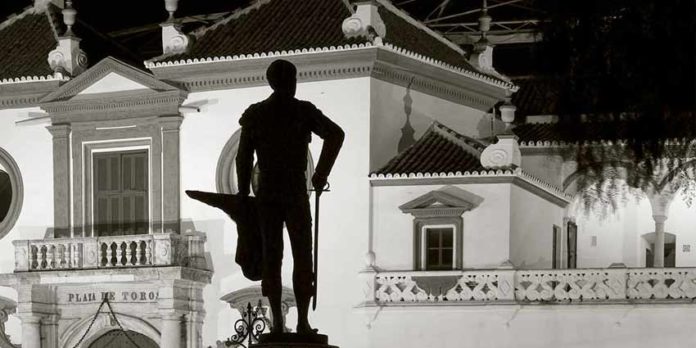 La silueta del monumento de Pepe Luis, con la muleta hecha un cartucho de pescado, se perfila frente a la Maestranza.